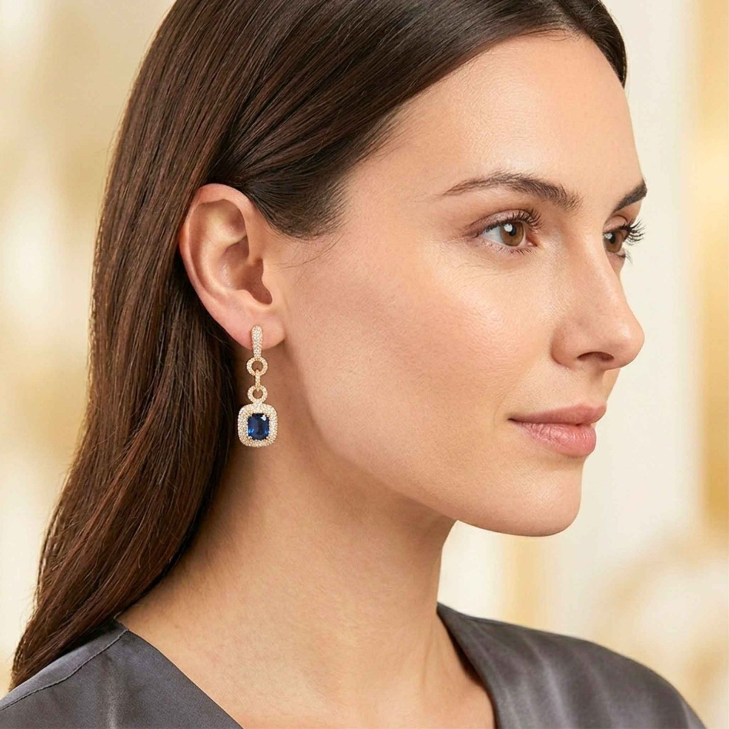 Woman wearing a pair of sapphire blue earrings with a soft background. Digitally rendered model for scale