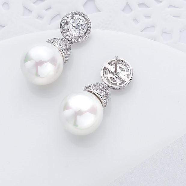 Pearl earrings with white gold and sparkling gem stones on a light background