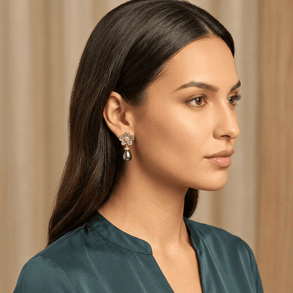 Woman wearing a pair of black pearl earrings with a beige curtain background