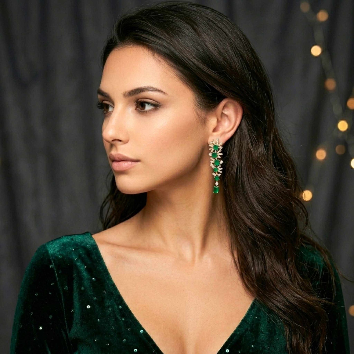 Woman wearing green earrings and a green dress with a dark background. Digitally rendered person wearing authentic jewellery.