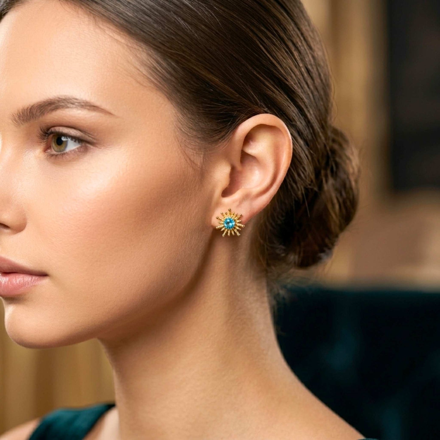 Close-up of a woman wearing a gold earring with a blue gemstone. Digitally rendered person wearing authentic jewellery.
