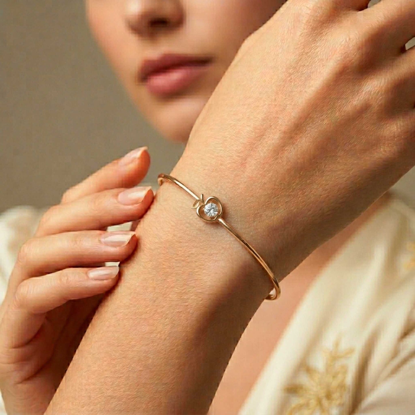 Close-up of a woman's wrist wearing a   openwork apple outline centrepiece set with a central brilliant round cubic zirconia stone.  Digitally rendered model for scale