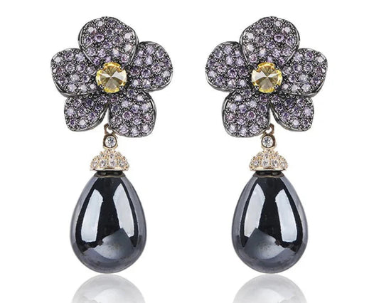 Pearl drop earrings with a main dark grey gemstone hung from a beautiful floral arrangement of delicate pinks and yellow gemstone against a white background. 
