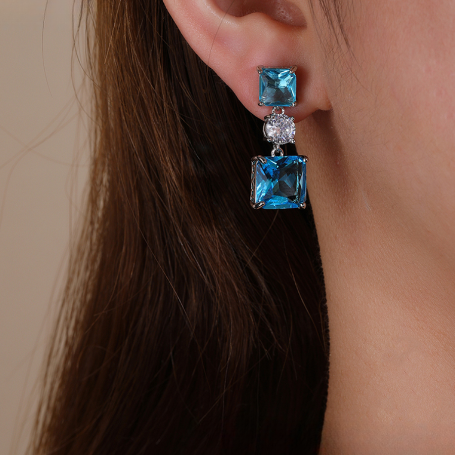 Blue earring worn by a person with brown hair.