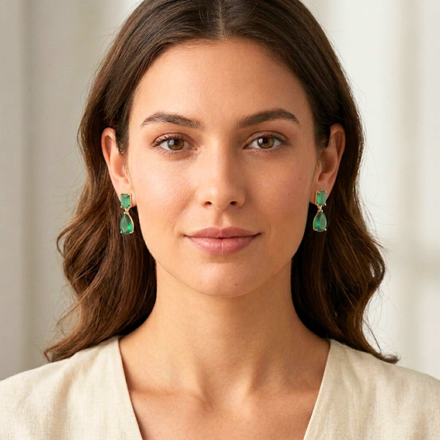 Woman wearing green earrings with a neutral background.  Digitally rendered model for scale.