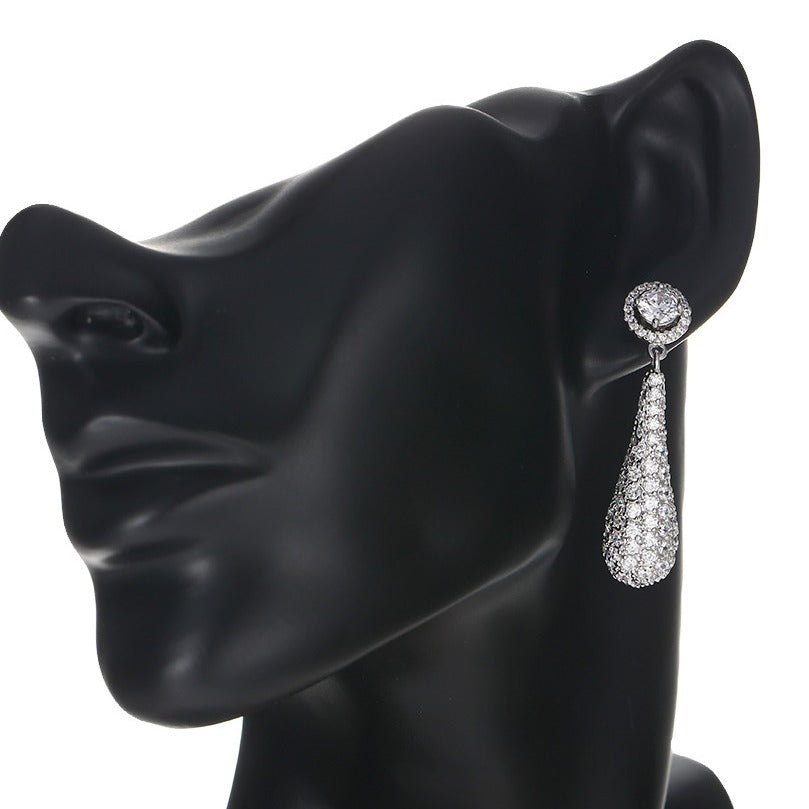 White gold teardrop earring on a model against a white background