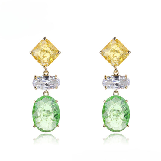 Pair of earrings with yellow, clear, and green gemstones on a white background