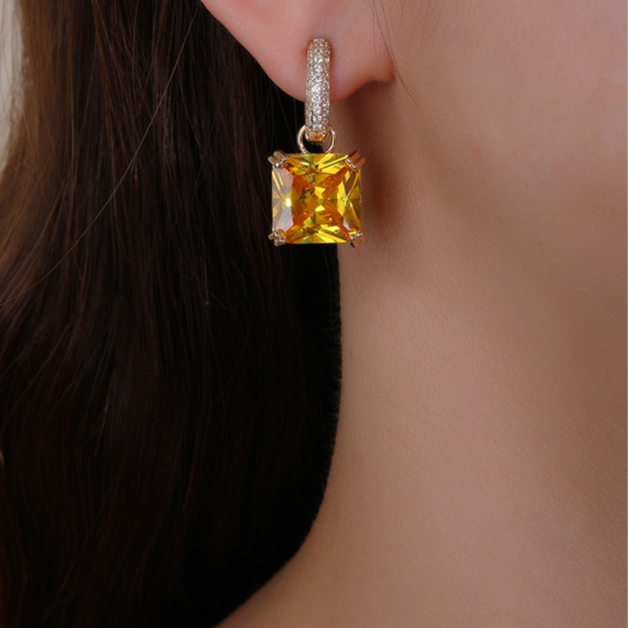 Yellow zirconia stone earring worn by a person with dark hair.