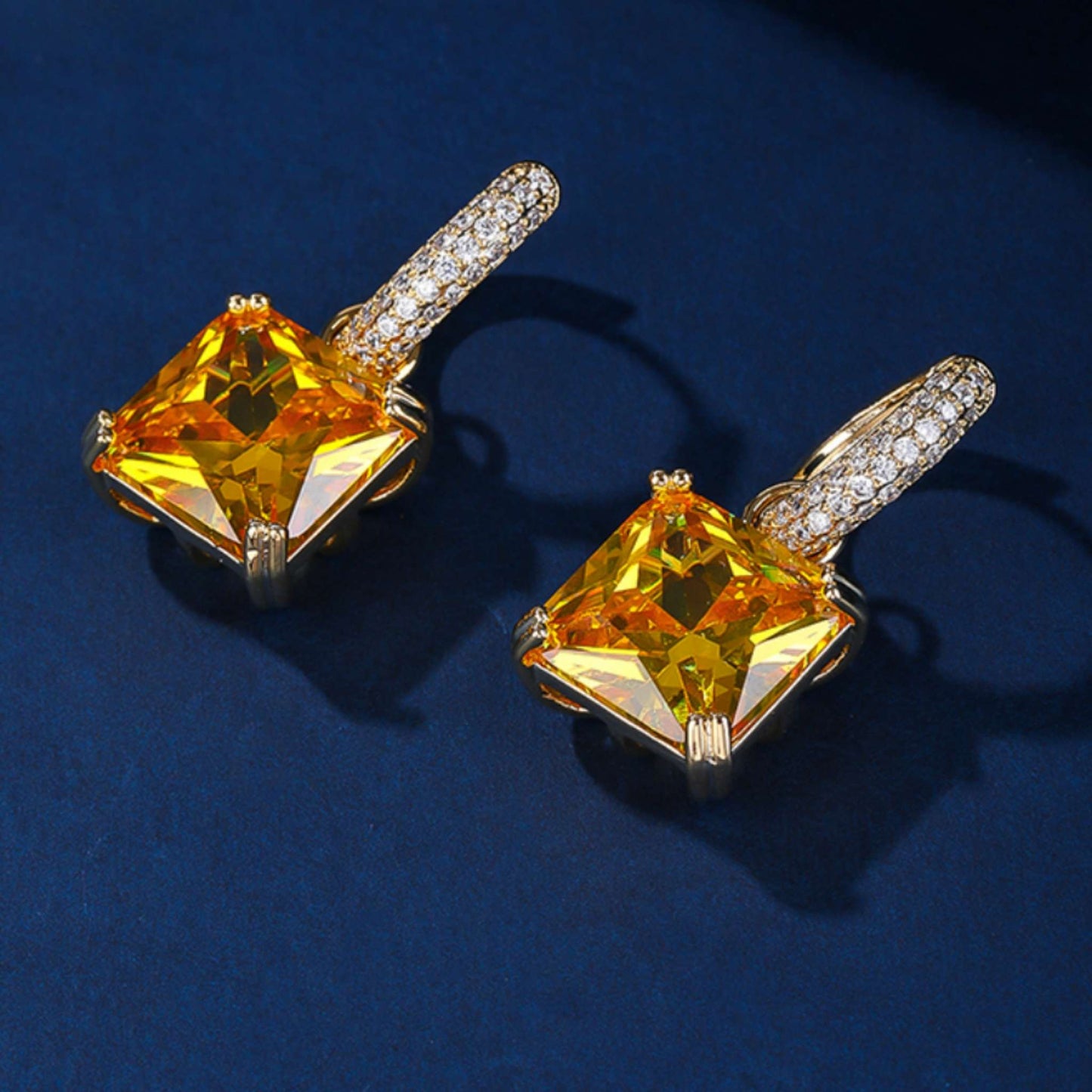 Yellow topaz earrings set against a blue background.