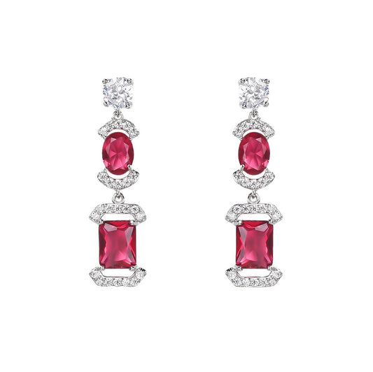 Pair of drop earrings with red gem stones and sparkling gem stones accents on a white background
