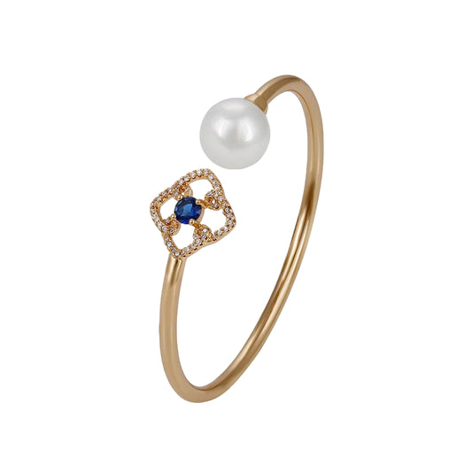 An 18k gold plated bracelet featuring a white pearl and blue zircon stone, with additional sparkling zirconia stones.