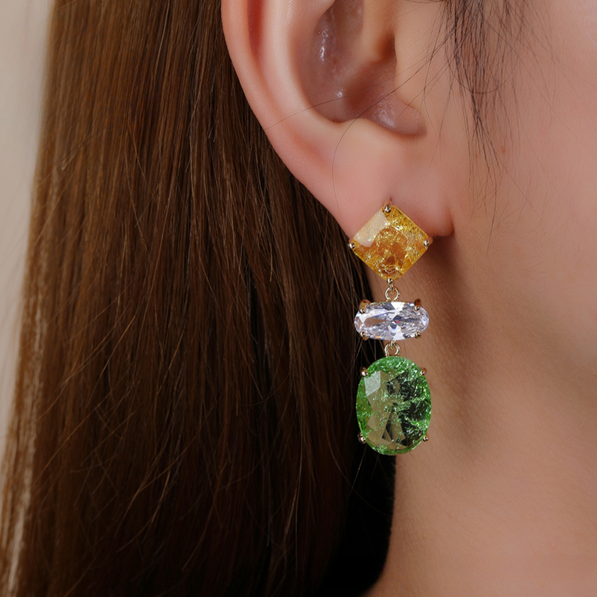 Close-up of an ear wearing a colourful gemstone earring.