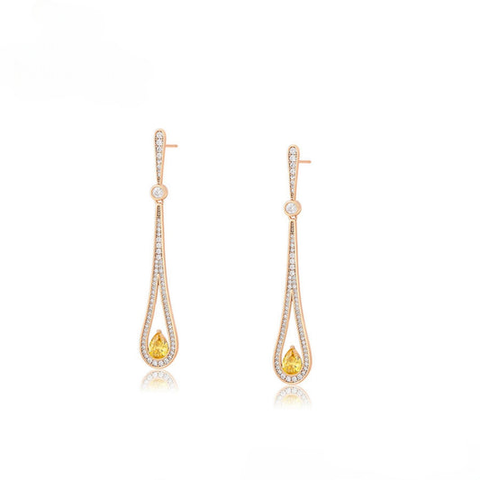 Pair of gold teat drop earrings with arrangement of clear gemstones and yellow gemstone.