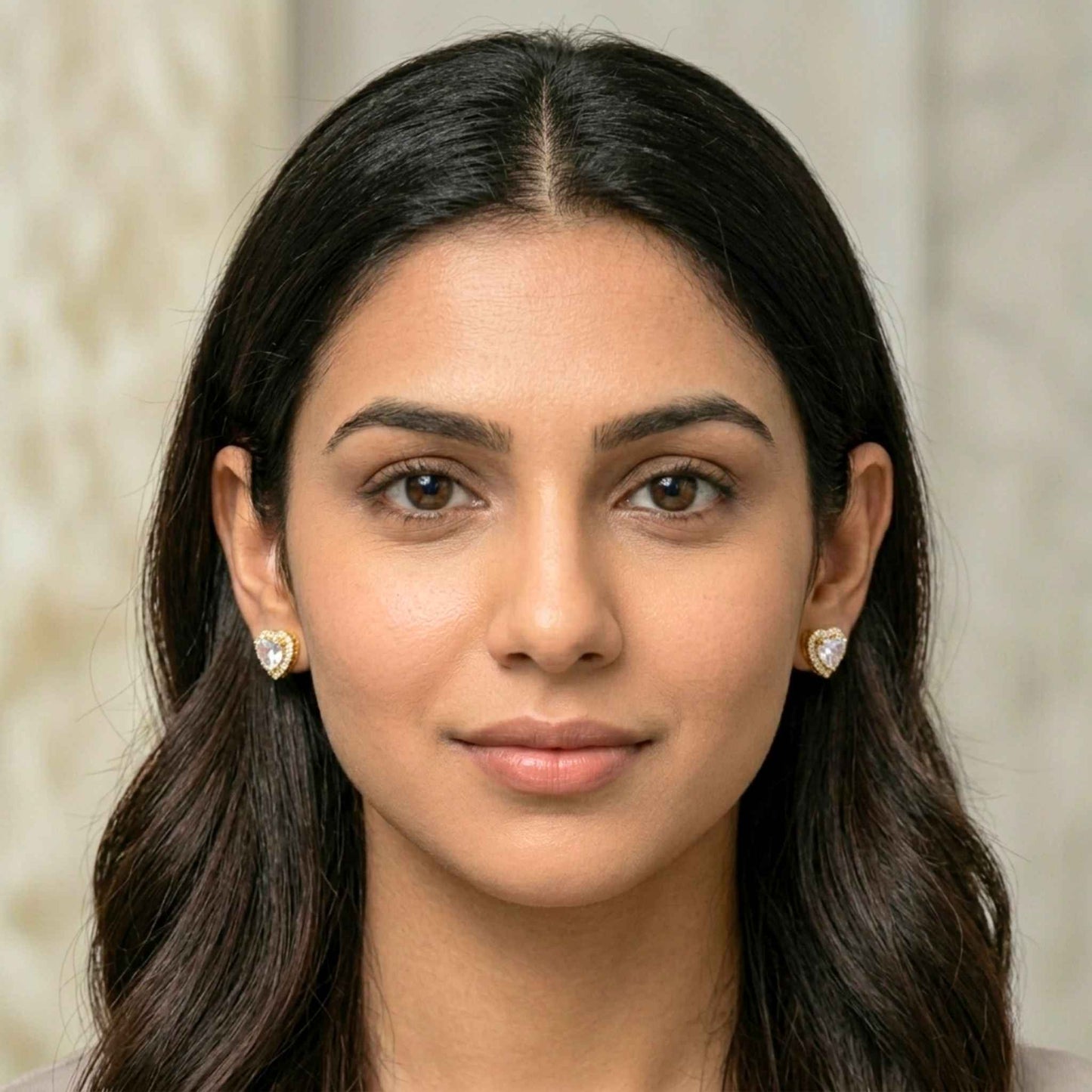 Close-up of a woman with long dark hair wearing heart-shaped earrings against a neutral background.  Digitally rendered model for scale