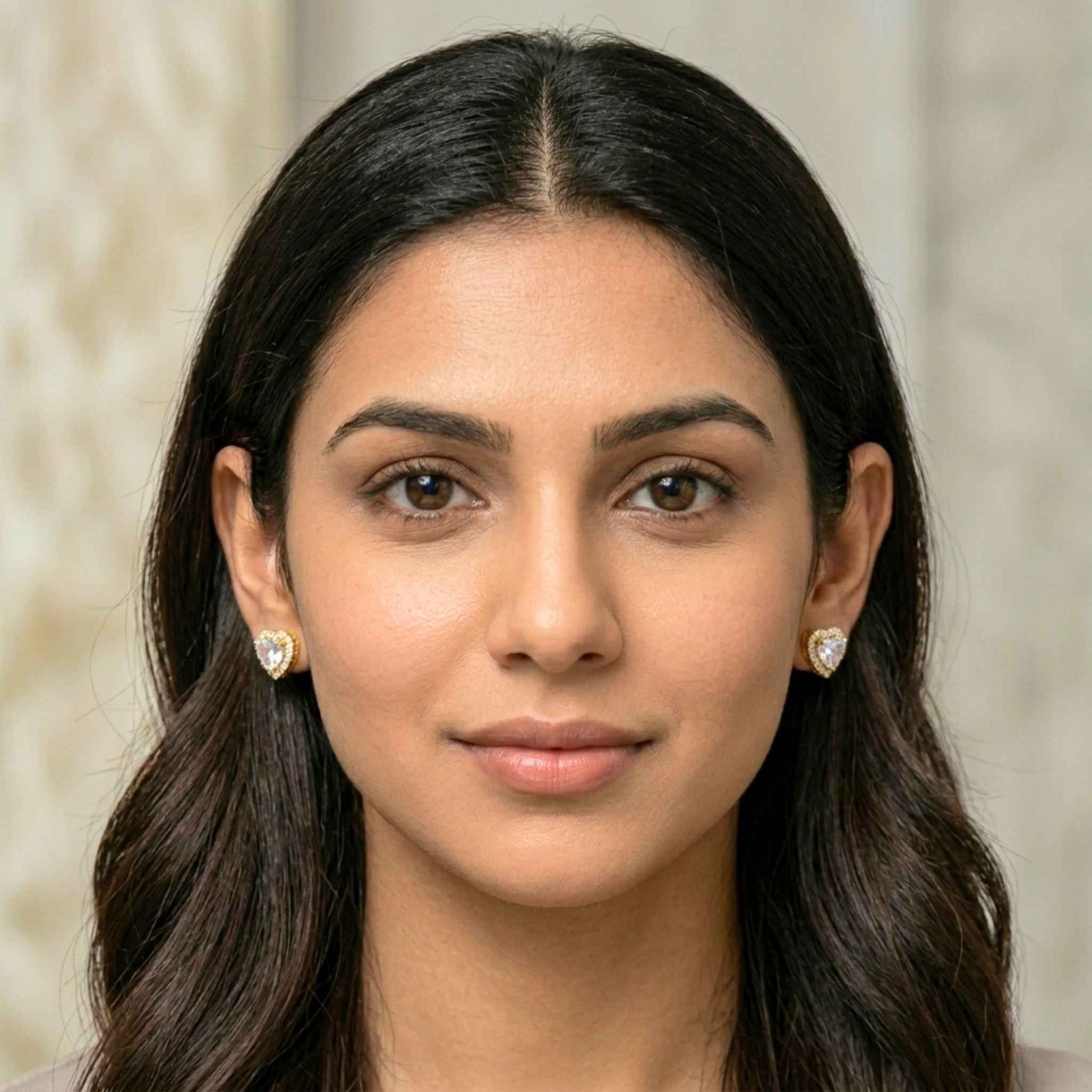 Close-up of a woman with long dark hair wearing heart-shaped earrings against a neutral background.  Digitally rendered model for scale