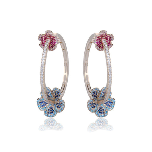 Pair of hoop earrings with floral designs featuring red and blue gemstones on a white background.