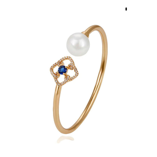 An 18k gold plated bracelet featuring a white pearl and blue cubic zirconia gemstone which is accentuated with sparkling gemstones.