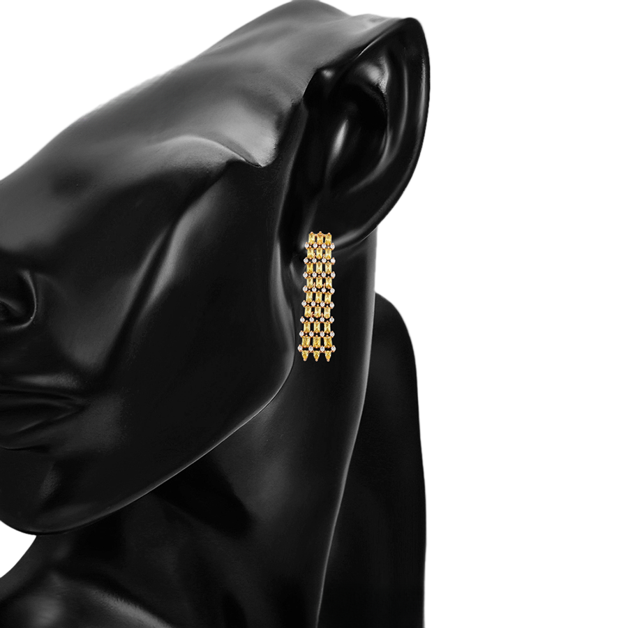 Gold earrings with sparkling yellow and white gemstones on a model with a light background