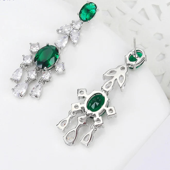 White gold plated earrings with green and clear gemstones on a white background.