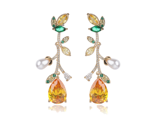 Pair of earrings with orange teardrop stones, green and white gemstones, and pearls on a white background