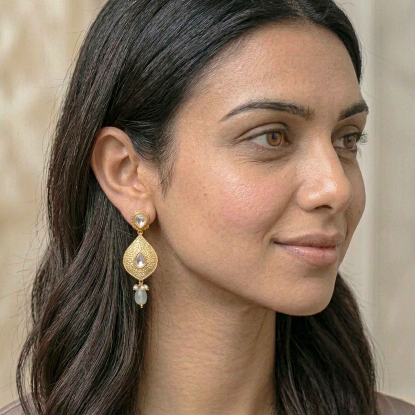 Woman wearing gold earrings with a neutral background.  Digitally rendered model for scale.