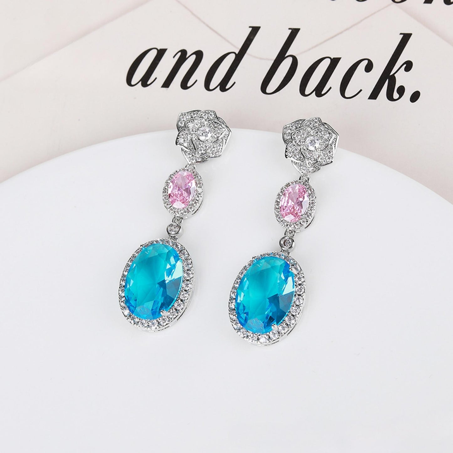 Pair of earrings with blue and pink gemstones on a white surface.