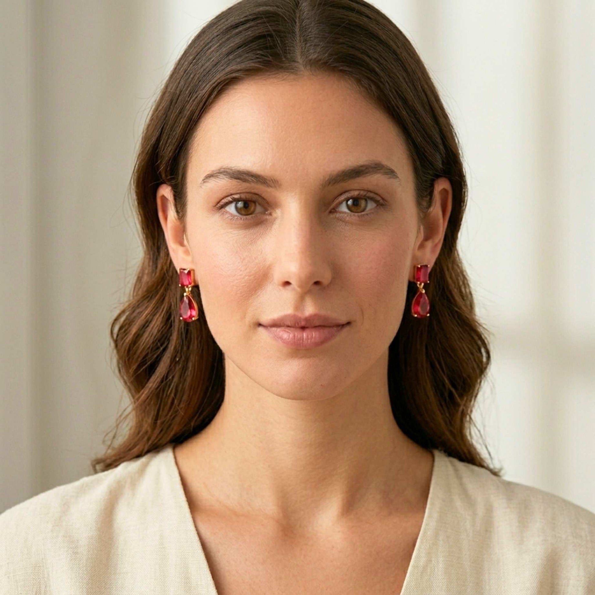 Woman wearing red earrings against a neutral background.  Digitally rendered model for scale.