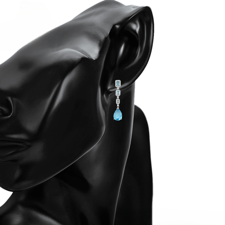 Teardrop sapphire blue earrings on a model against a white background.