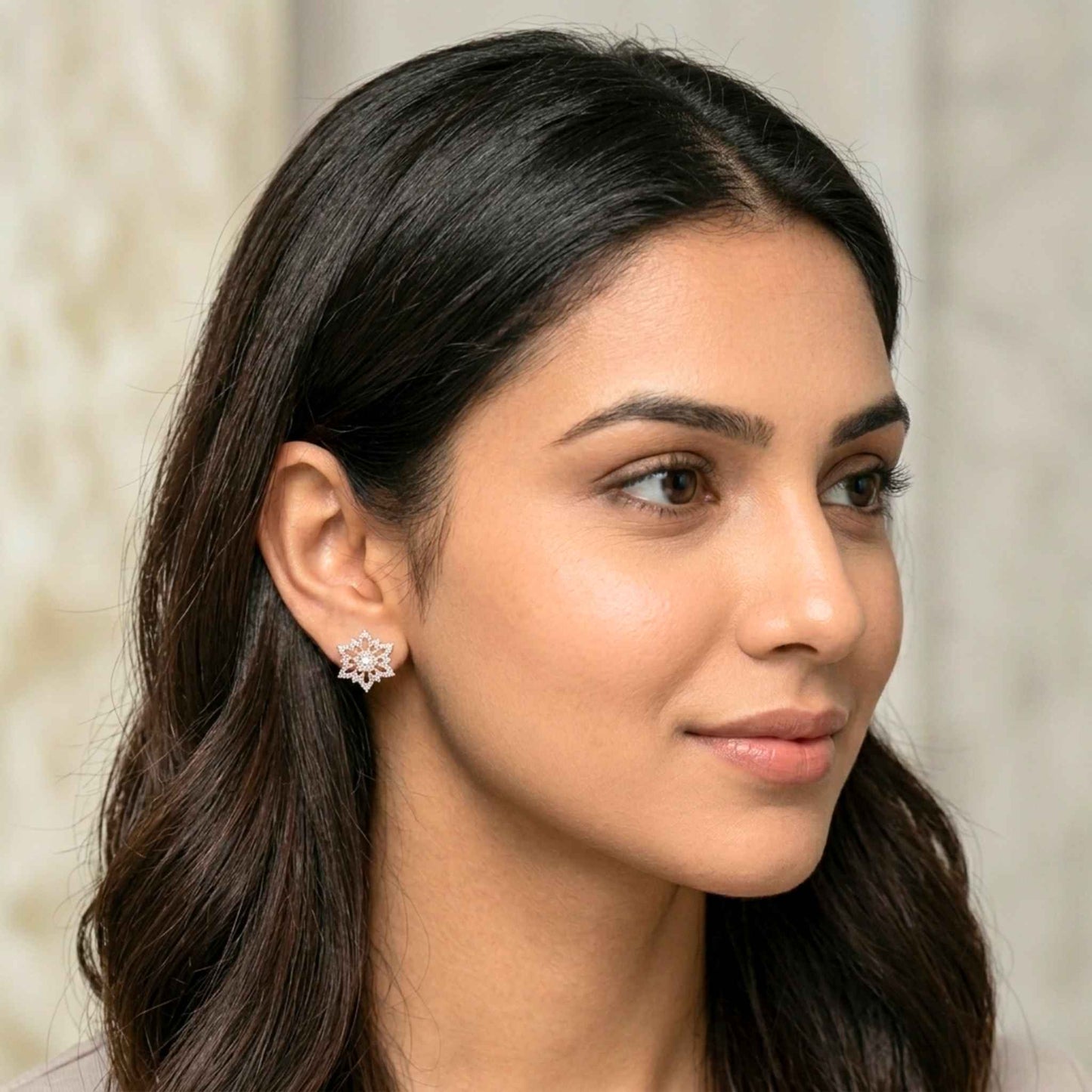 Woman wearing a start design earring with a neutral background.  Digitally rendered model for scale.