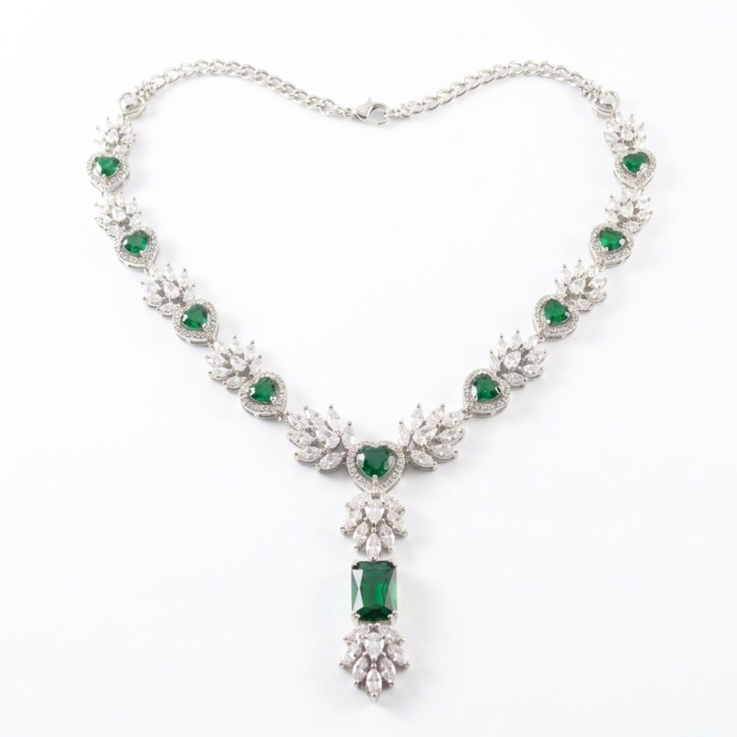 Elegant necklace with emerald green gemstones and silver chain on a white background