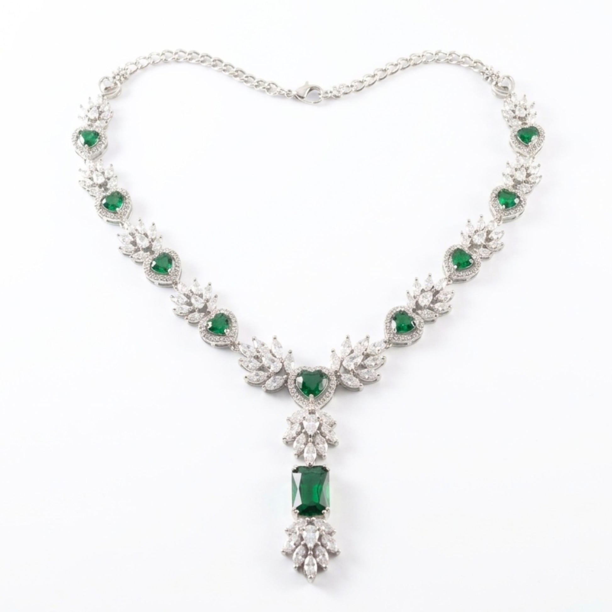 Elegant necklace with emerald green gemstones and silver chain on a white background