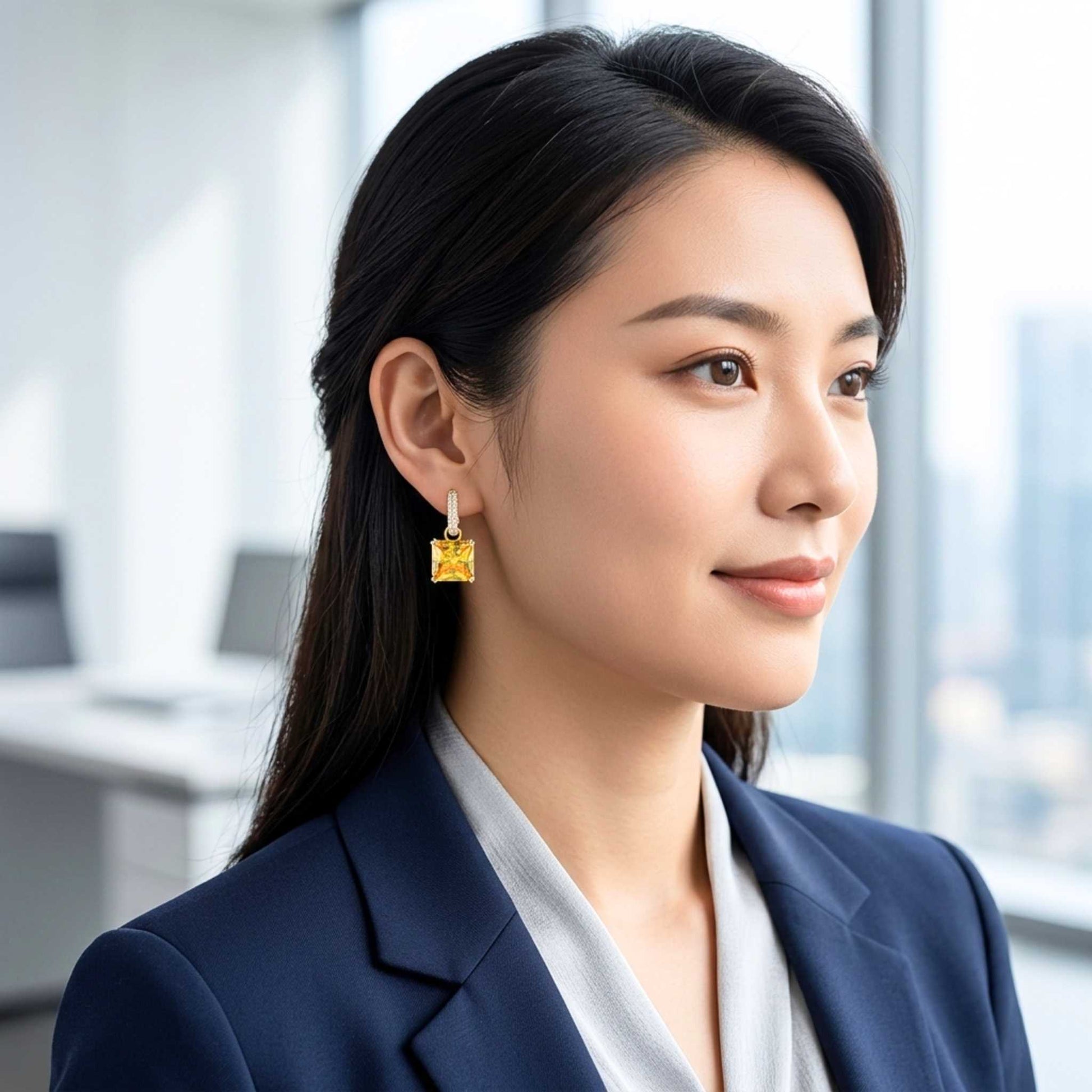 Yellow earrings on a woman in a work blazer set against a blurred office background.  Digitally rendered model for scale.