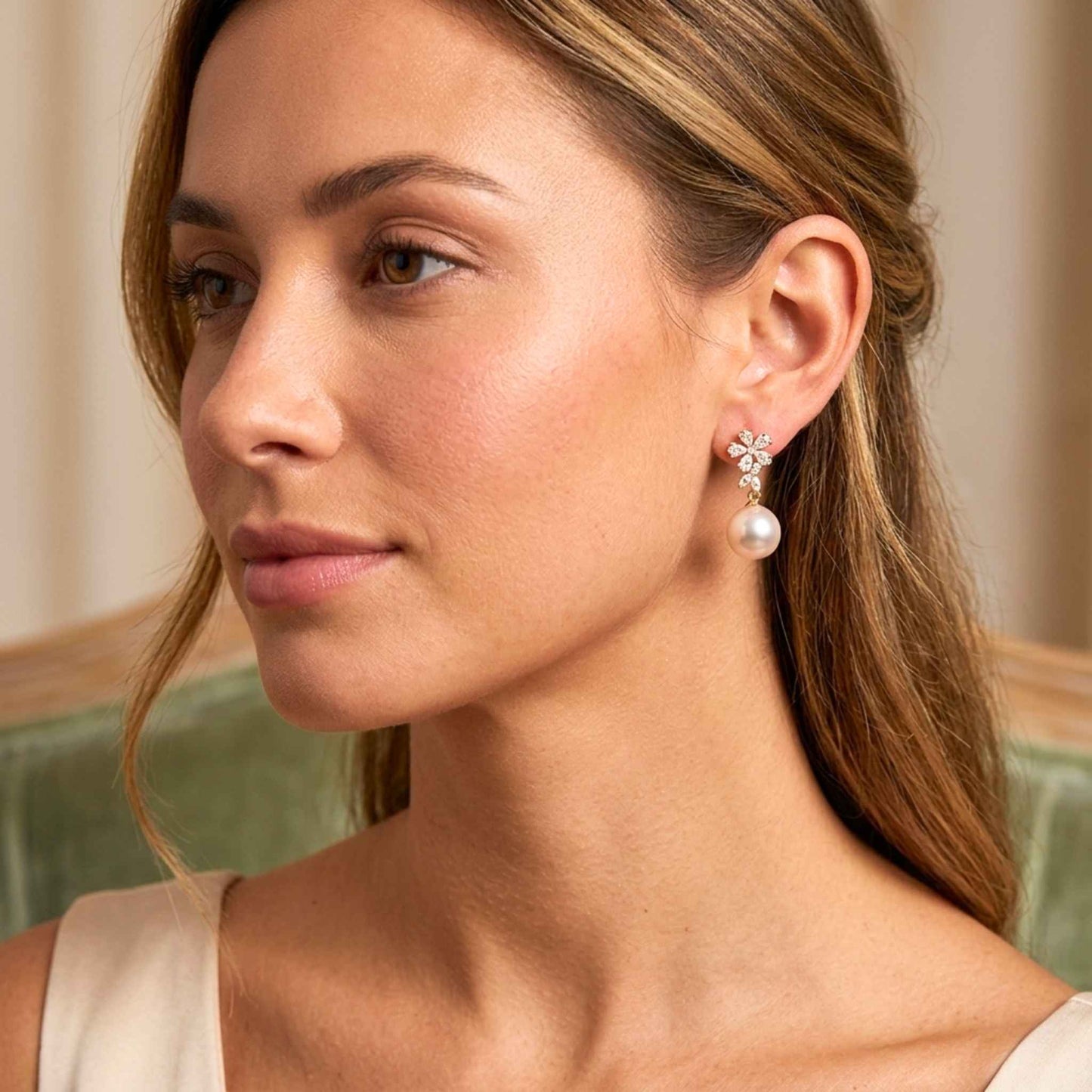 Close-up of a woman wearing pearl earrings with cz gemstones against a neutral background.   Digitally rendered model for scale