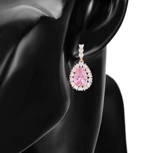 Earrings in pink presented in a pear shape on a model.