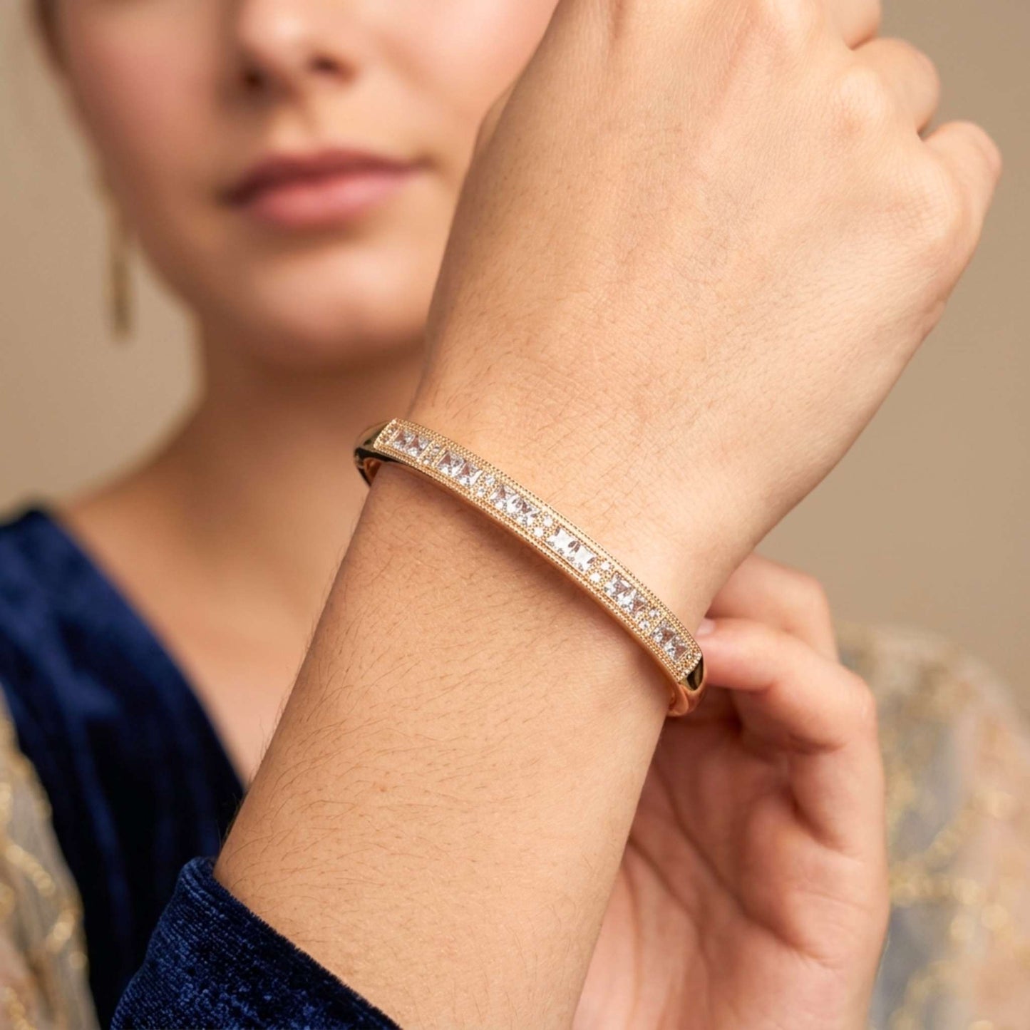 Women's wrist showing a gold bangle bracelet with sparkling gemstones from the Jewellery 4 Elegance collection.  Digitally rendered model for scale.