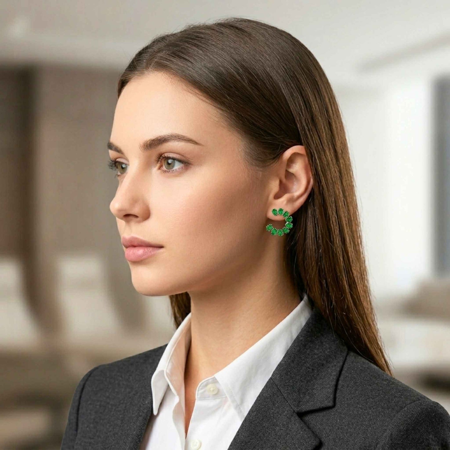 Woman wearing gold open hoop green earrings from Jewellery 4 Elegance collection set against a blurred background.  Digitally rendered model for scale