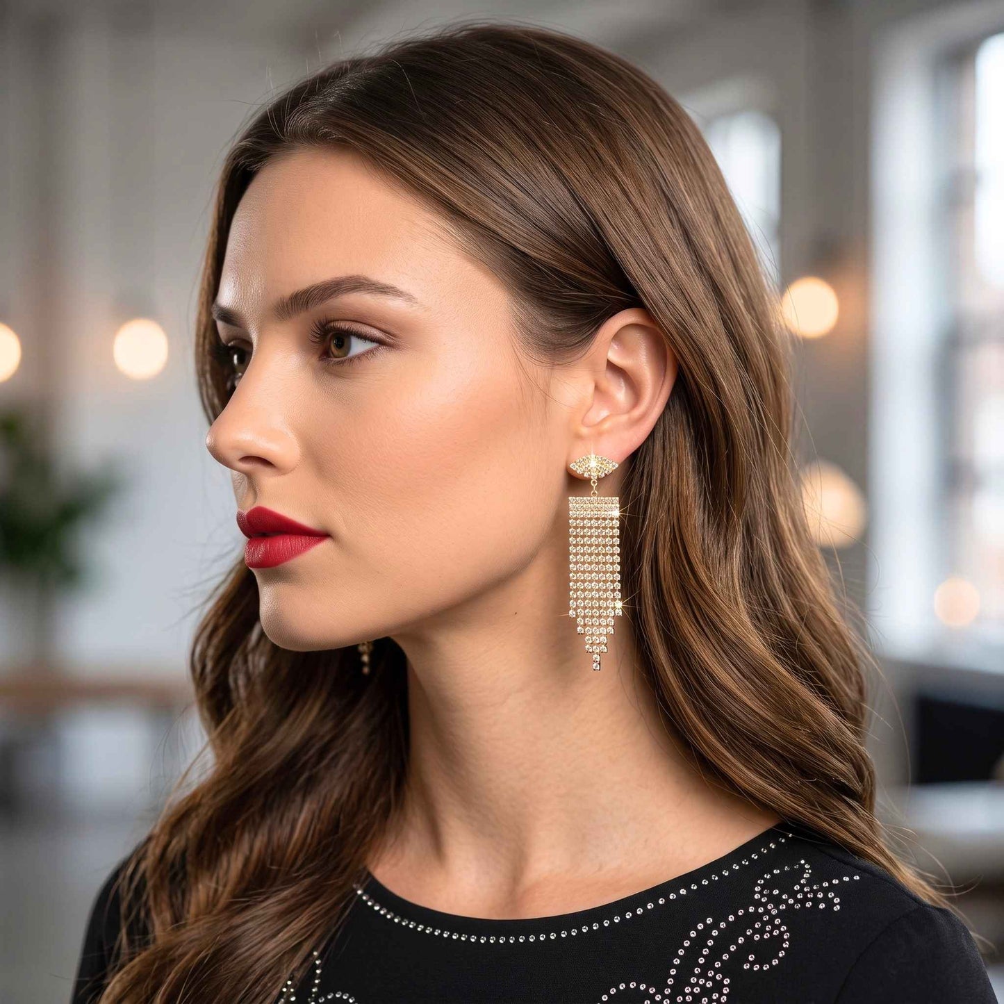 An elegant woman wearing a pair of elegant gold plated dangle earrings featuring shimmering cubic zirconia gemstones in a multi-strand chandelier design from the jewellery 4 Elegance collection set against blurred indoor setting.  Digitally rendered model for scale.