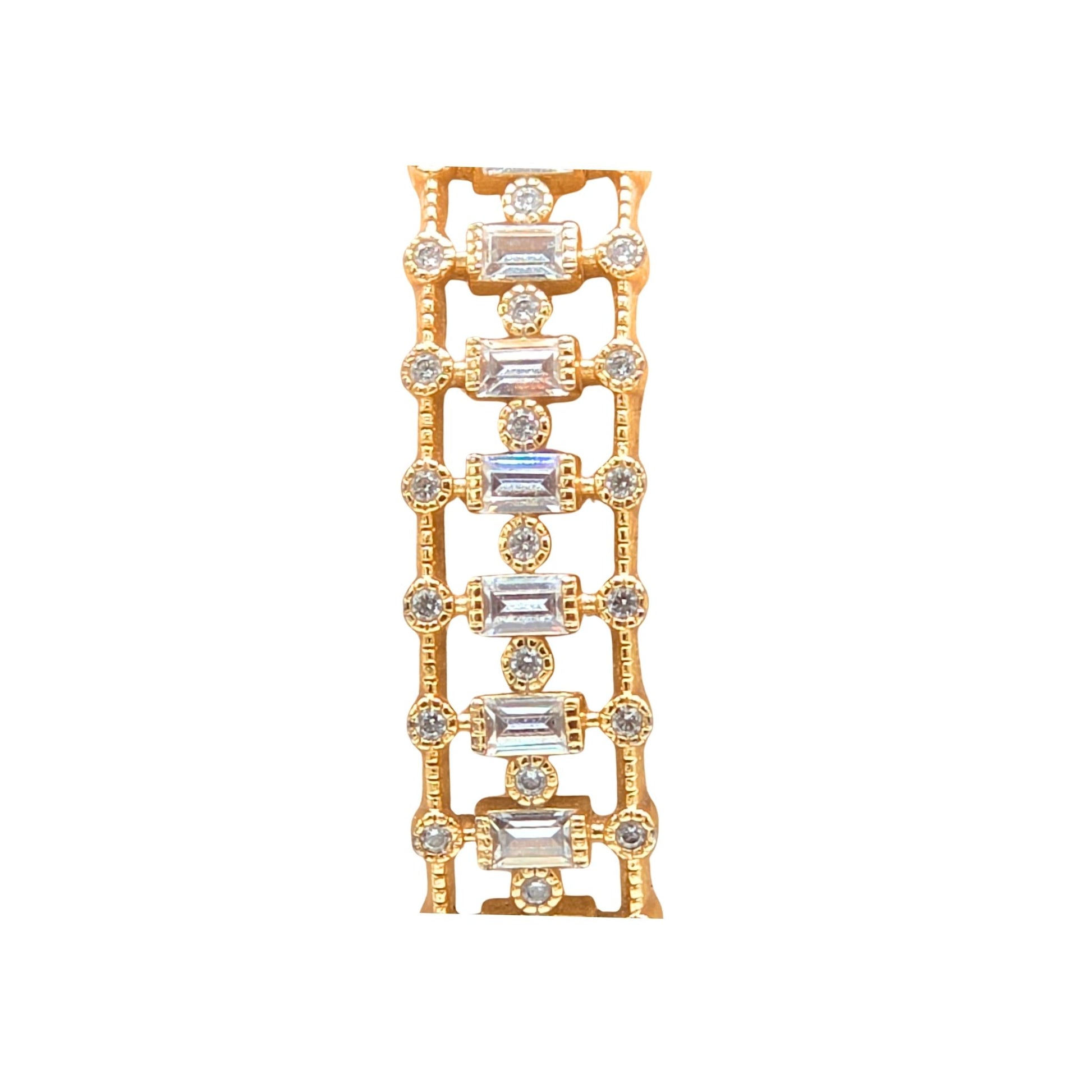 Close up of a Gold bangle bracelet featuring an intricate front band set with vertical baguette-cut and round brilliant-cut cubic zirconia gemstones, isolated on a white background