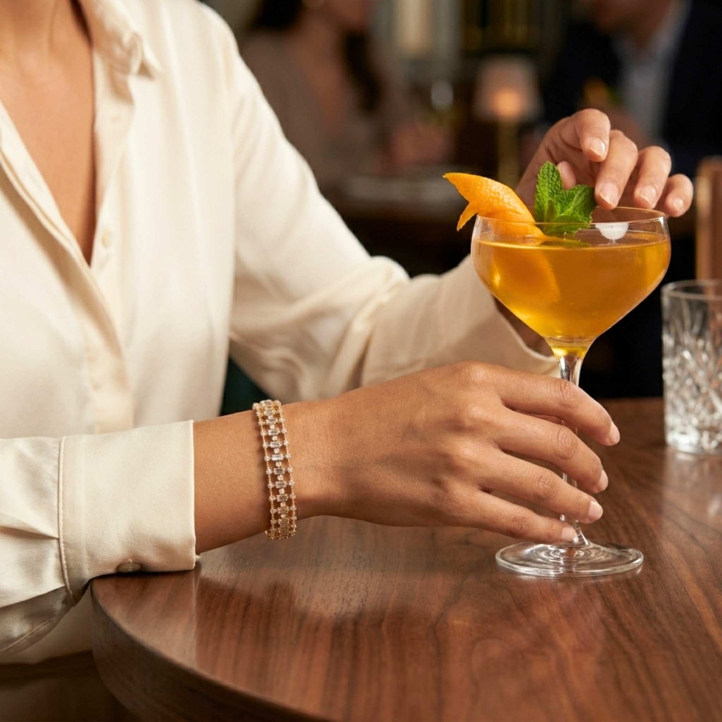 Women holding a cocktail wearing a gold bangle bracelet from Jewellery 4 Elegance bangle bracelet collection. Digitally rendered model for scale
