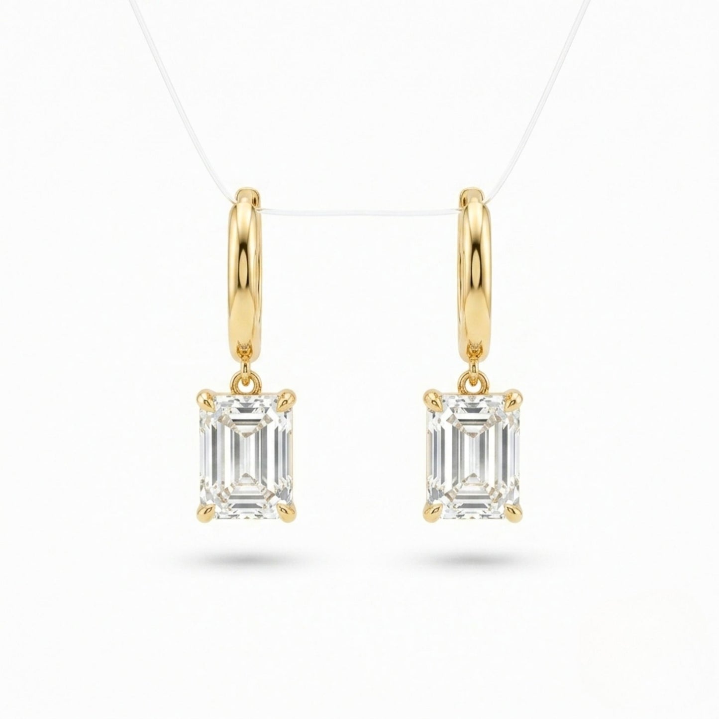 A pair of Jewellery 4 Elegance gold plated drop earrings featuring smooth huggie hoops suspending a brilliant emerald cut cubic zirconia gemstone on a white background