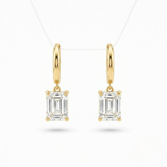 A pair of Jewellery 4 Elegance gold plated drop earrings featuring smooth huggie hoops suspending a brilliant emerald cut cubic zirconia gemstone on a white background