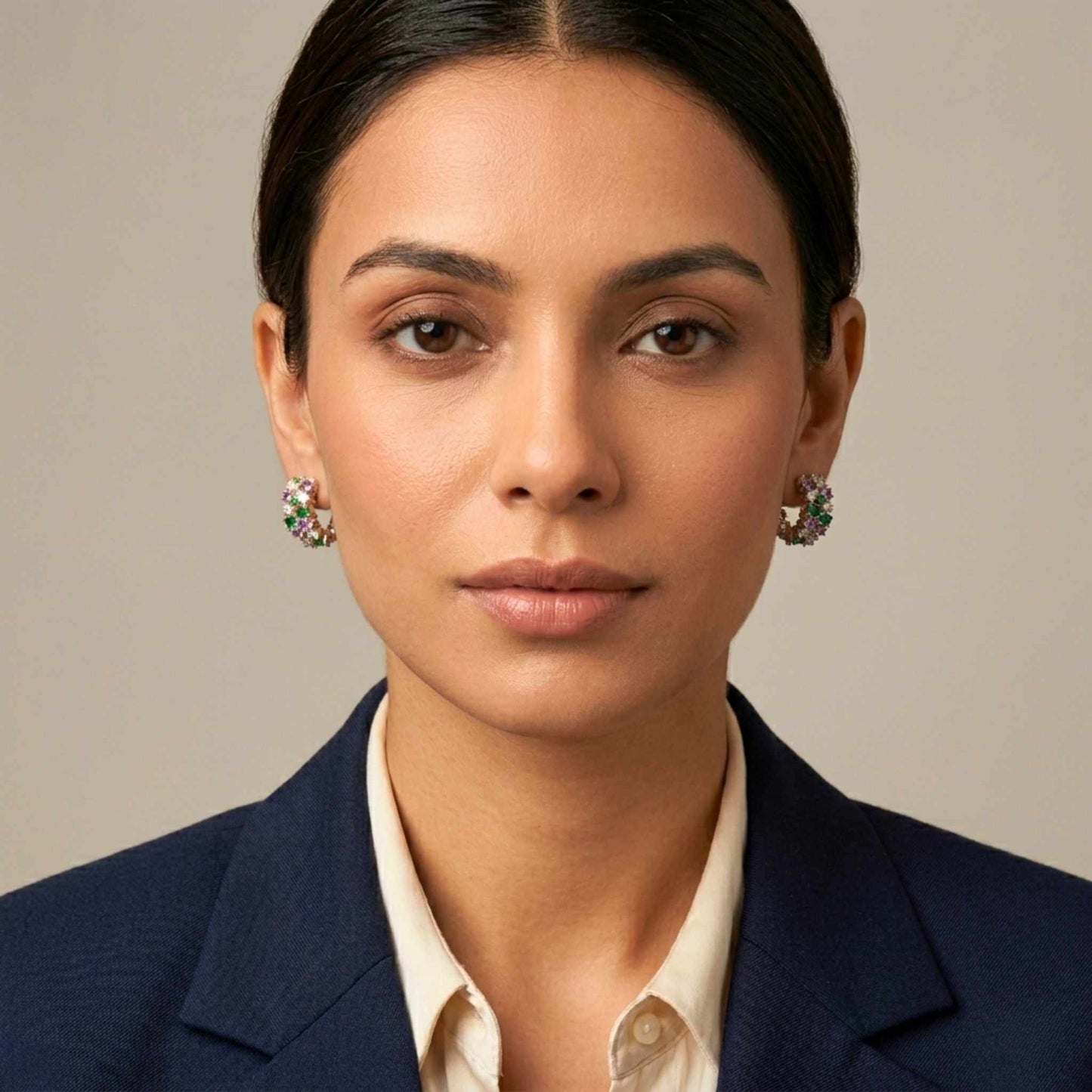 Woman wearing a navy blazer and white shirt with multicolour earrings from the Jewellery 4 Elegance collection set against a neutral background.  Digitally rendered model for scale