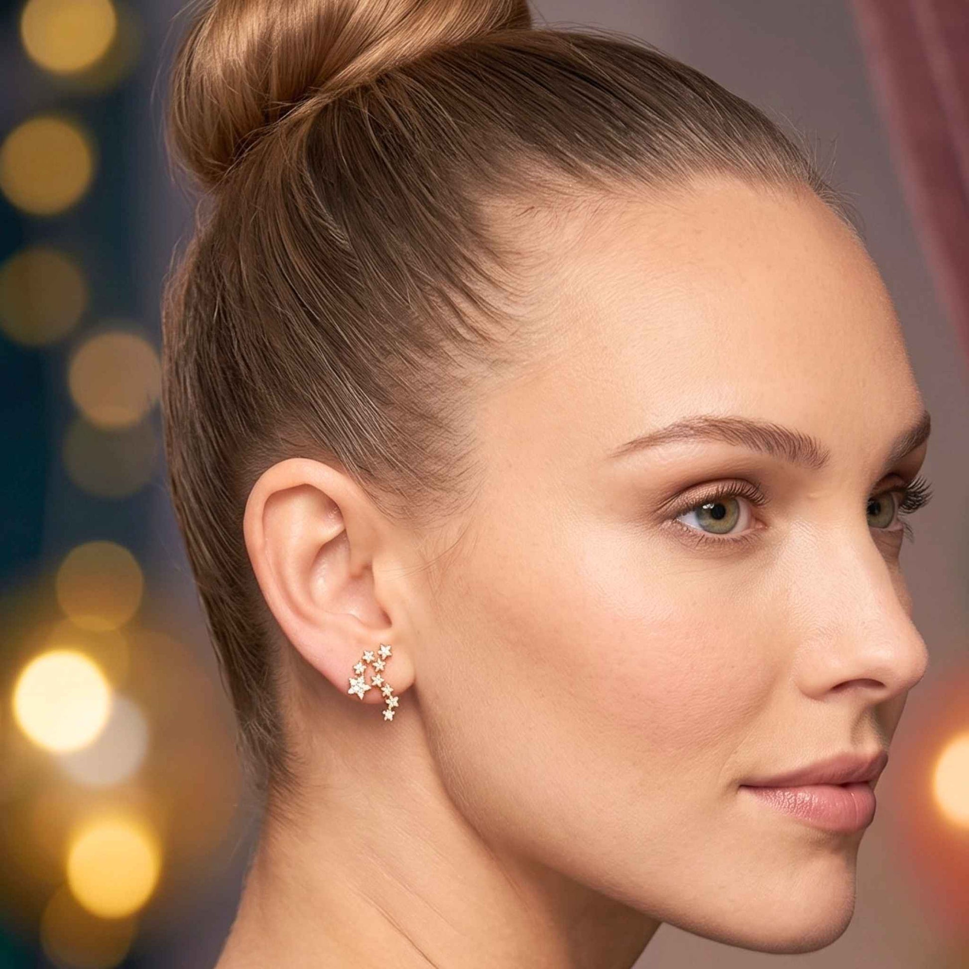 A close-up portrait of a woman with her hair in a high bun, wearing a pair of quality gold stud ear climber earrings in a fun constellation star cluster design embedded with glittering cubic zirconia from the Jewellery 4 Collection against a softly blurred background.  Digitally rendered model for scale