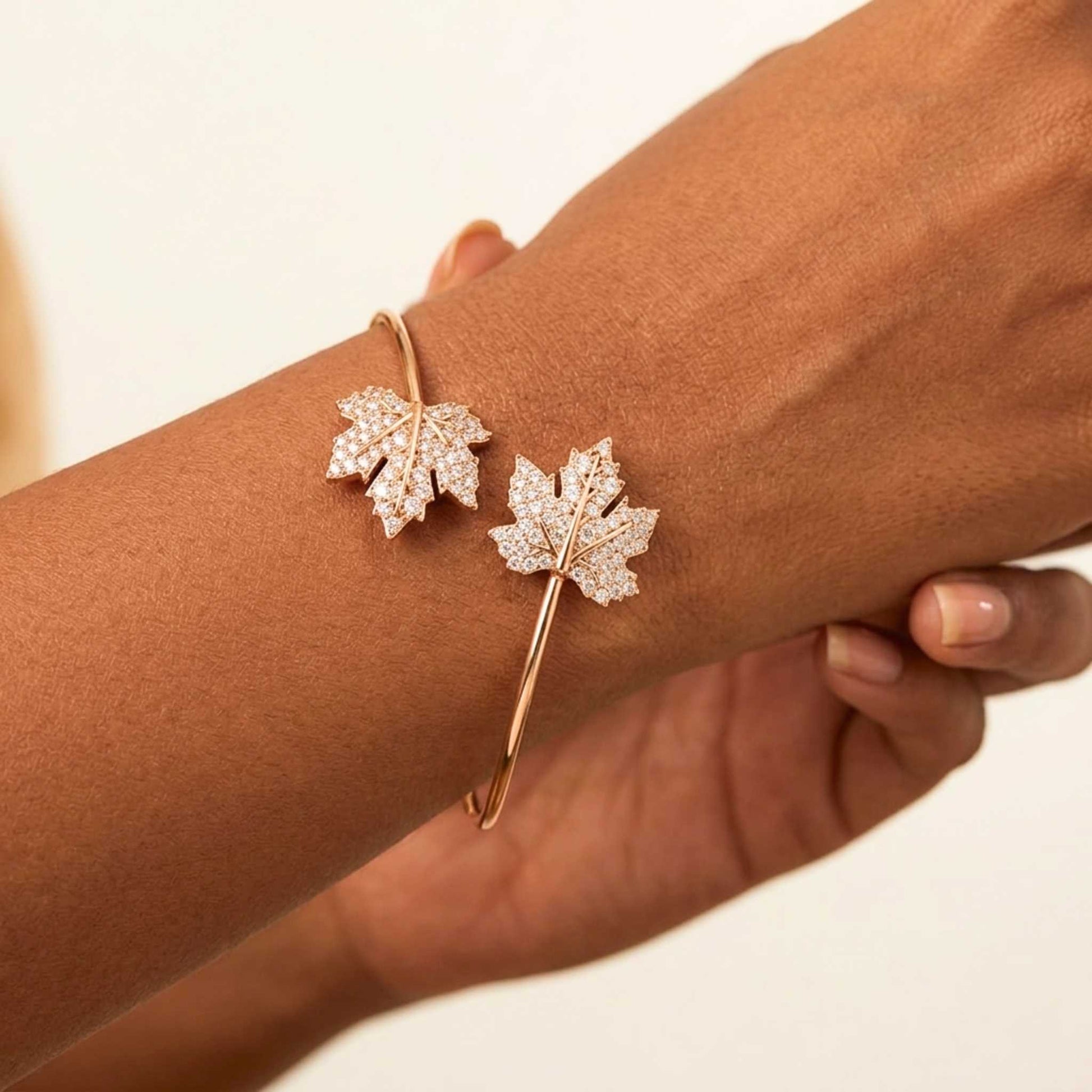 Rose gold leaf-shaped bracelet on a wrist against a beige background.  Digitally rendered model for scale