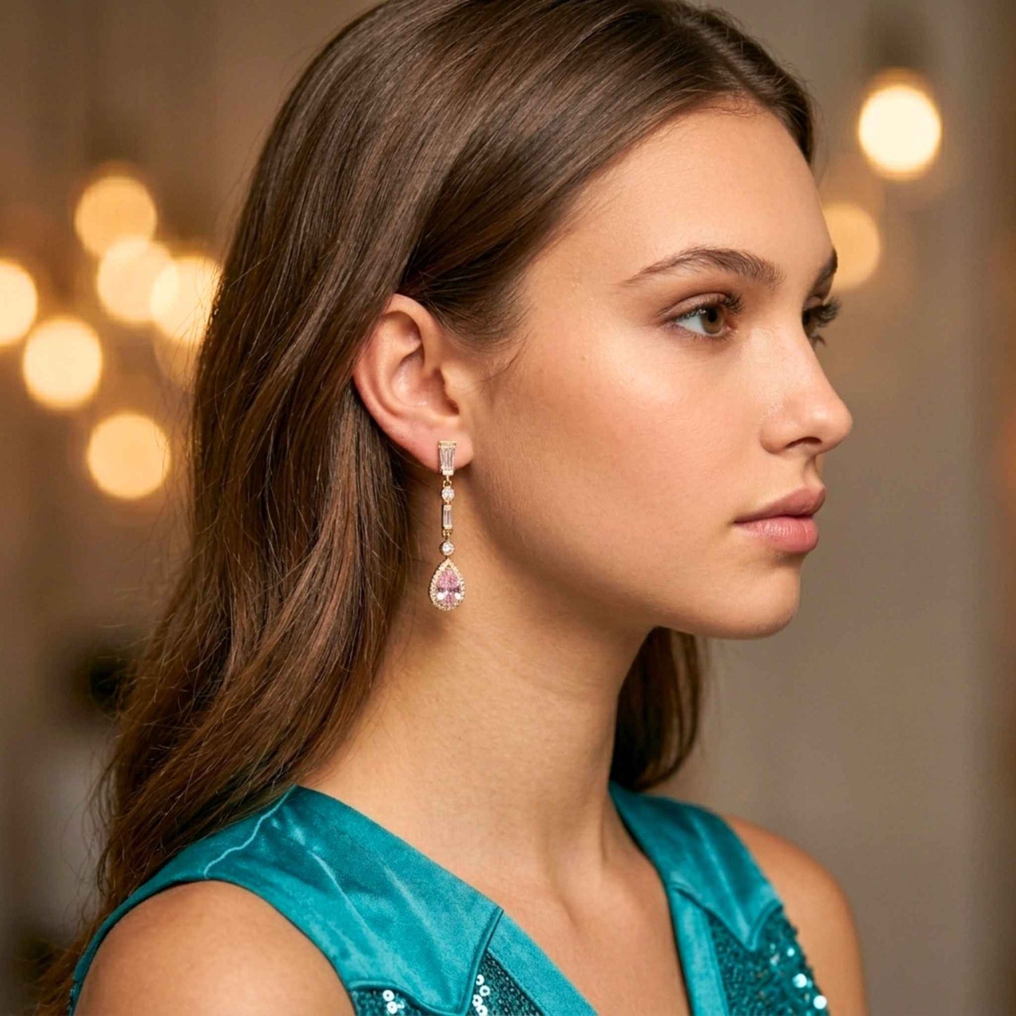 Woman wearing gold blush pink earrings earrings from the Jewellery 4 Elegance collection set against a blurred background.  Digitally rendered model for scale