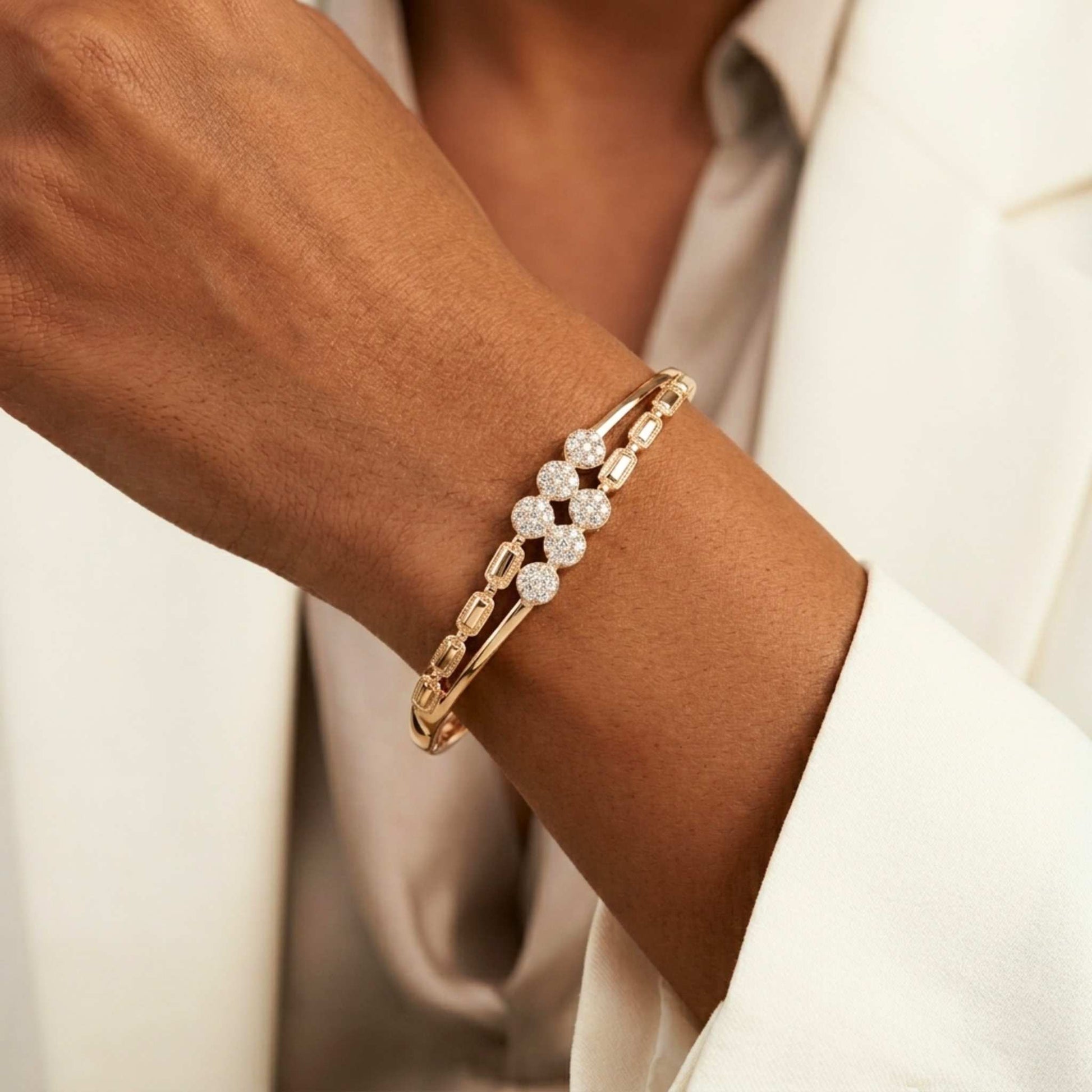 Close up of a women in a white jacket wearing a gold bangle bracelet with gemstones clusters from jewellery 4 Elegance collection.  Digitally rendered model for scale