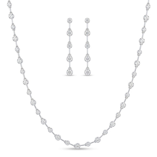 A white gold jewellery set featuring a delicate necklace and matching drop earrings, both adorned with clear round-cut stones, displayed on a clean white background.  From the jewellery f4 Elegance collection.